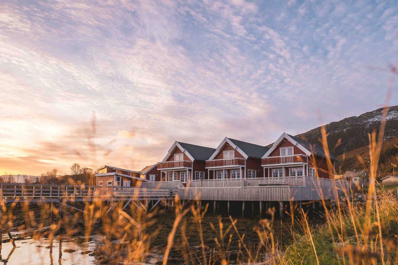 A waterfront property with a wooden deck, a dock, and a mountainous backdrop.