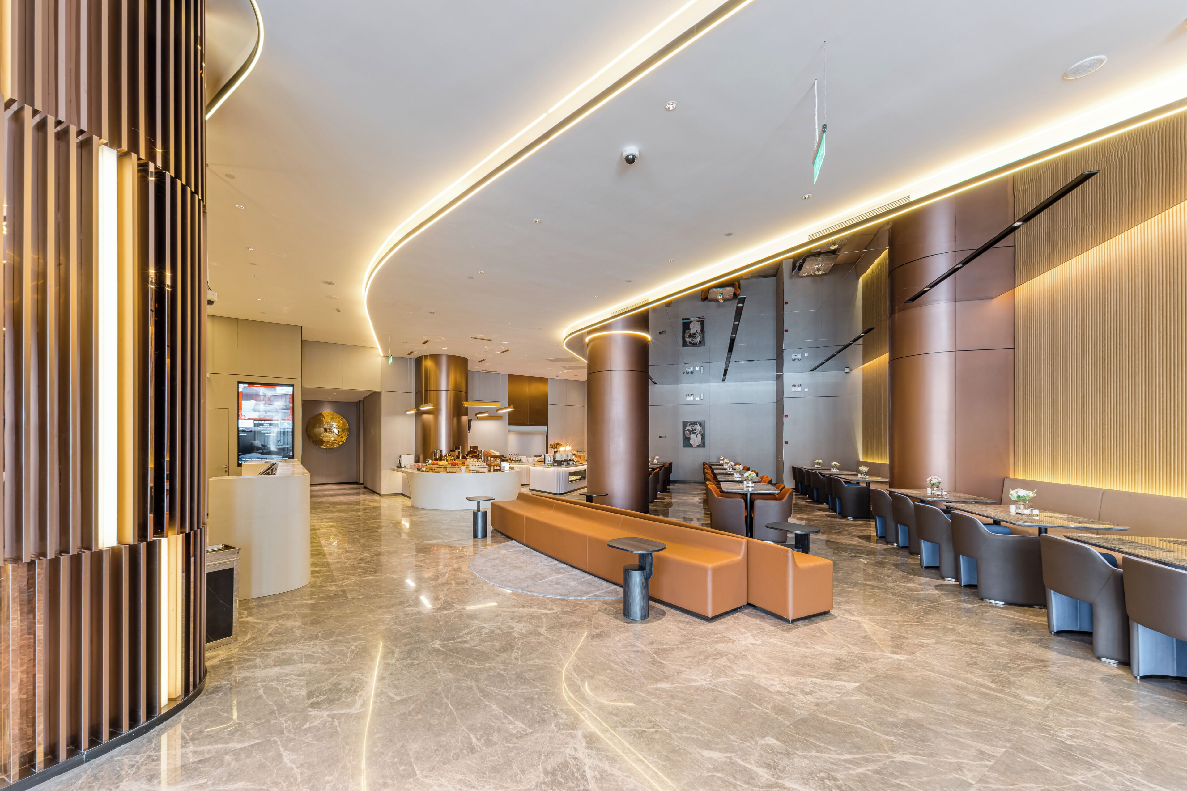 A modern lobby with a reception desk, seating area, and a large digital display.