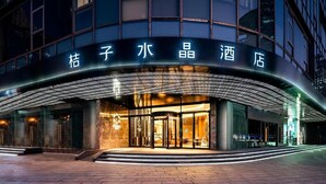 A hotel entrance with a modern design, featuring a glass facade and a curved roof structure.