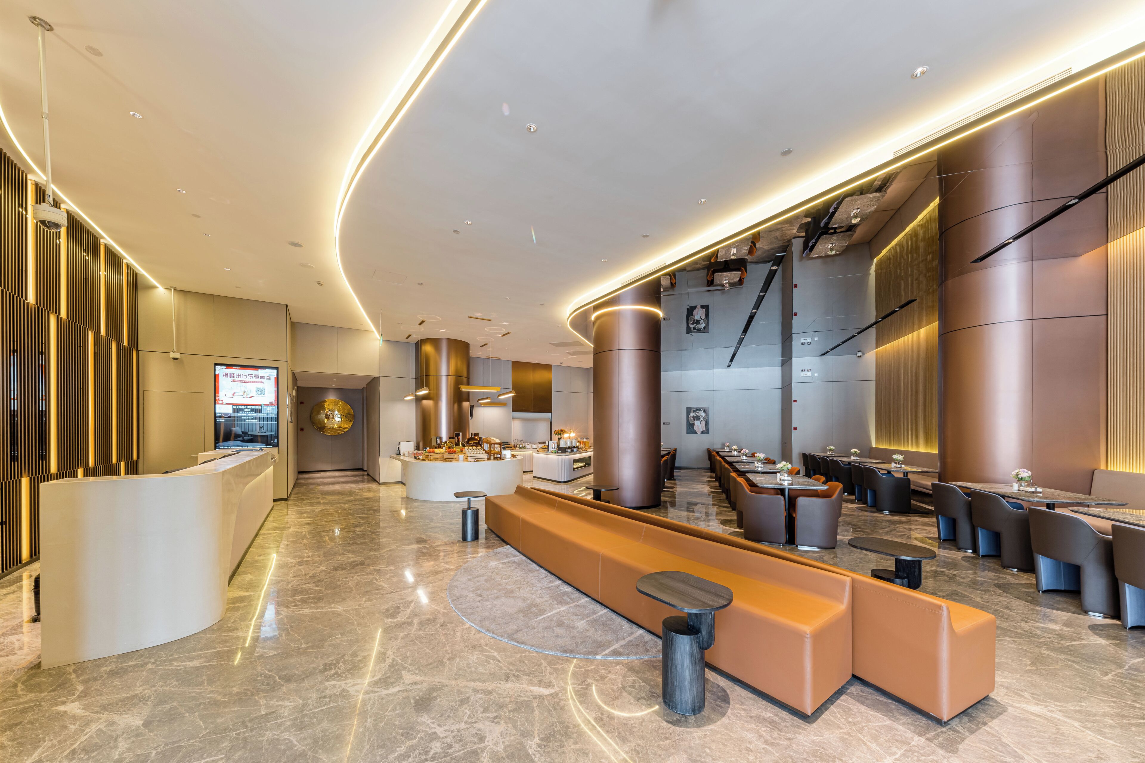 A modern hotel lobby with a reception desk, seating areas, and a staircase.
