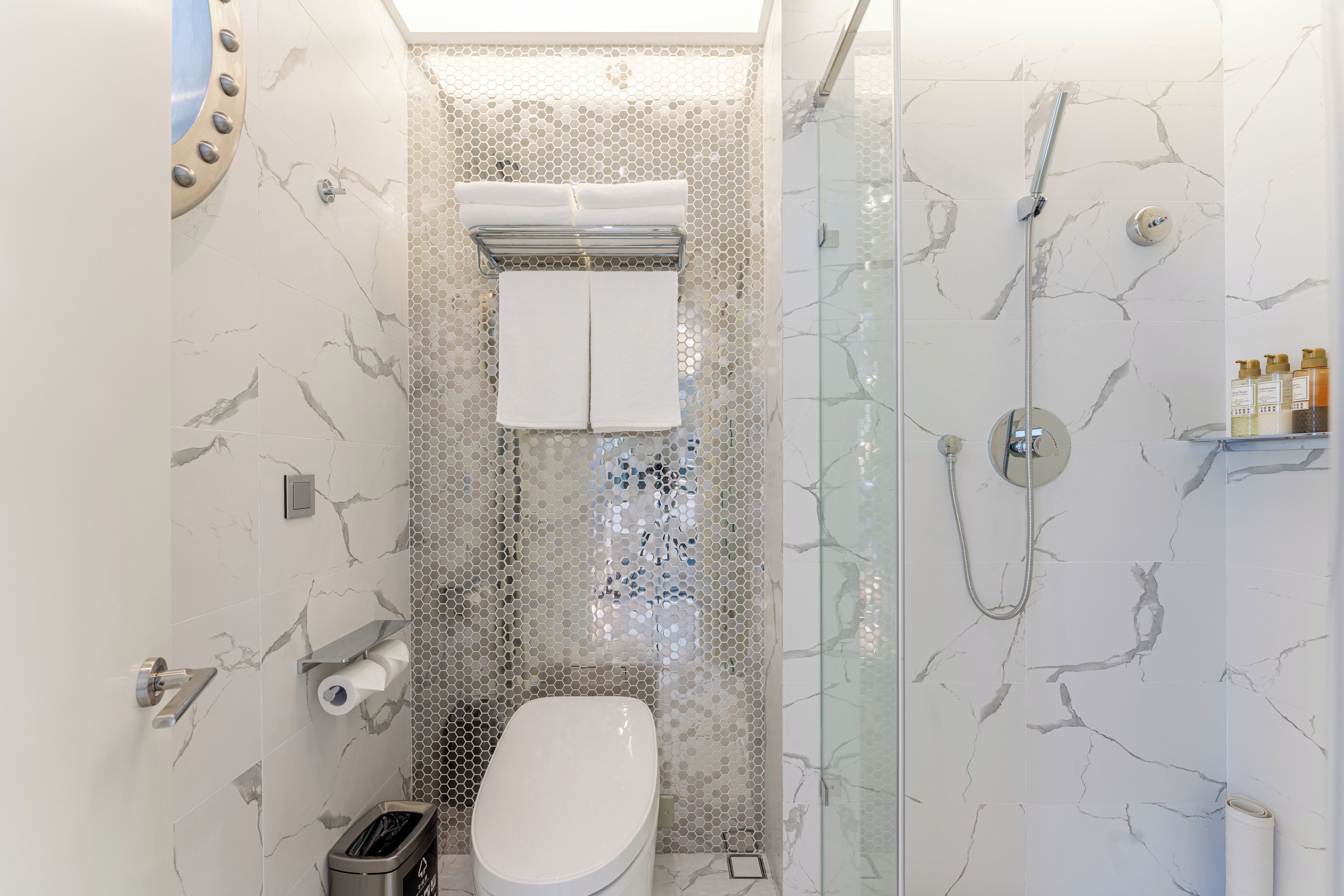 A modern bathroom with a toilet, shower, and glass-enclosed shower area.
