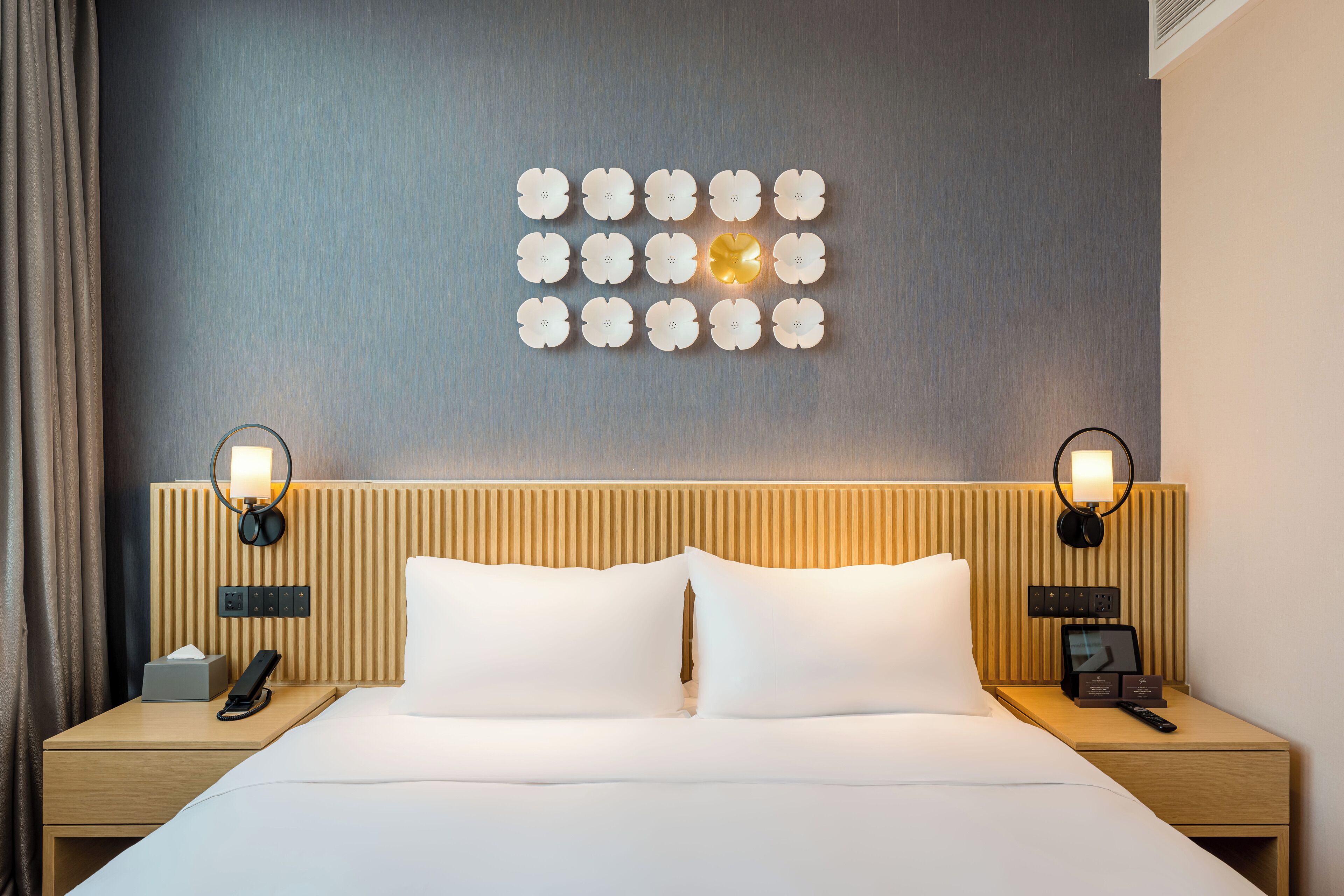 Ein Hotelzimmer mit einem Bett, zwei Nachttischen, einer Wanduhr und einer Wandlampe.