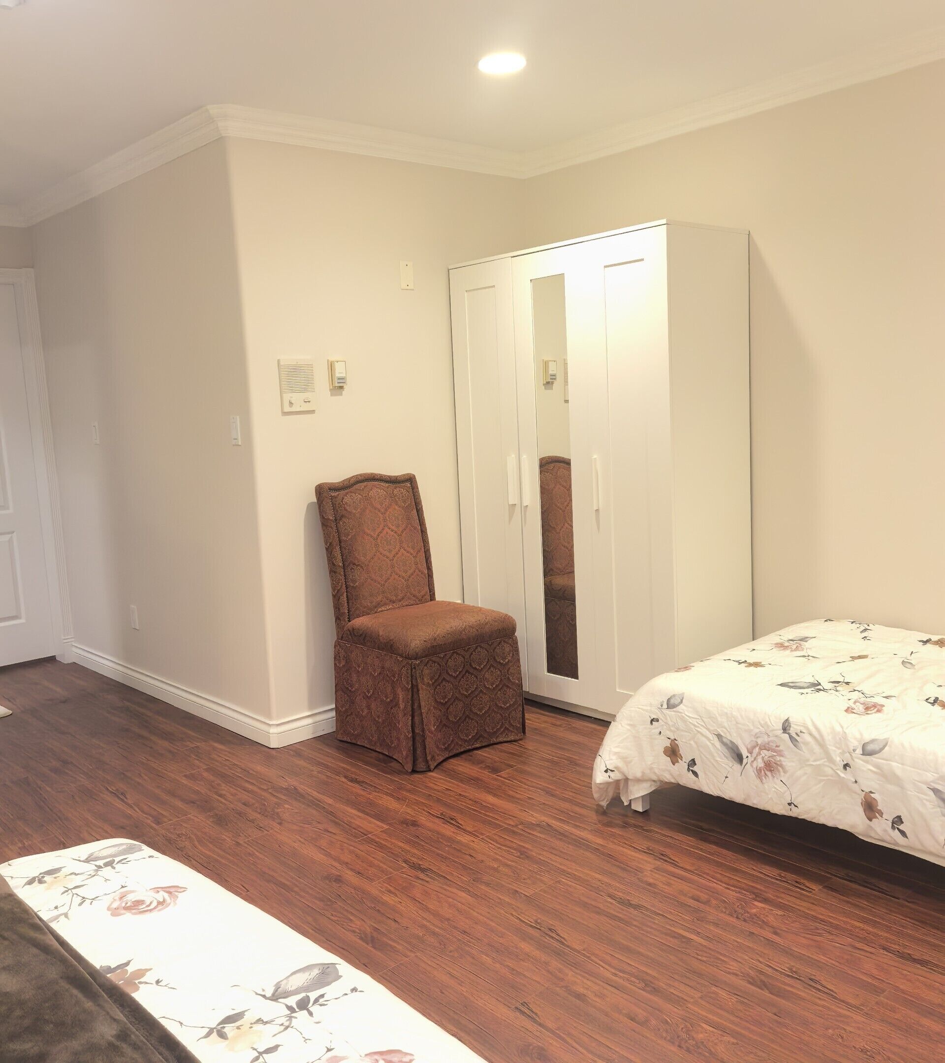A bedroom with a bed, a wardrobe, and a chair.