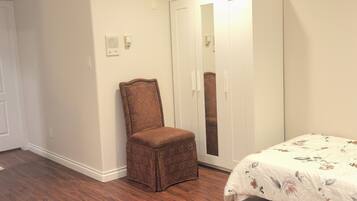 A bedroom with a bed, a wardrobe, and a chair.