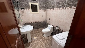 Et badeværelse med vask, toilet og et lille vindue.