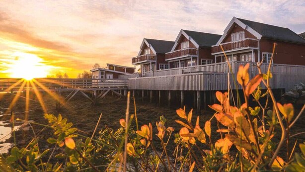 Une propriété située au bord de l’eau, comprenant plusieurs bâtiments reliés par une terrasse en bois.