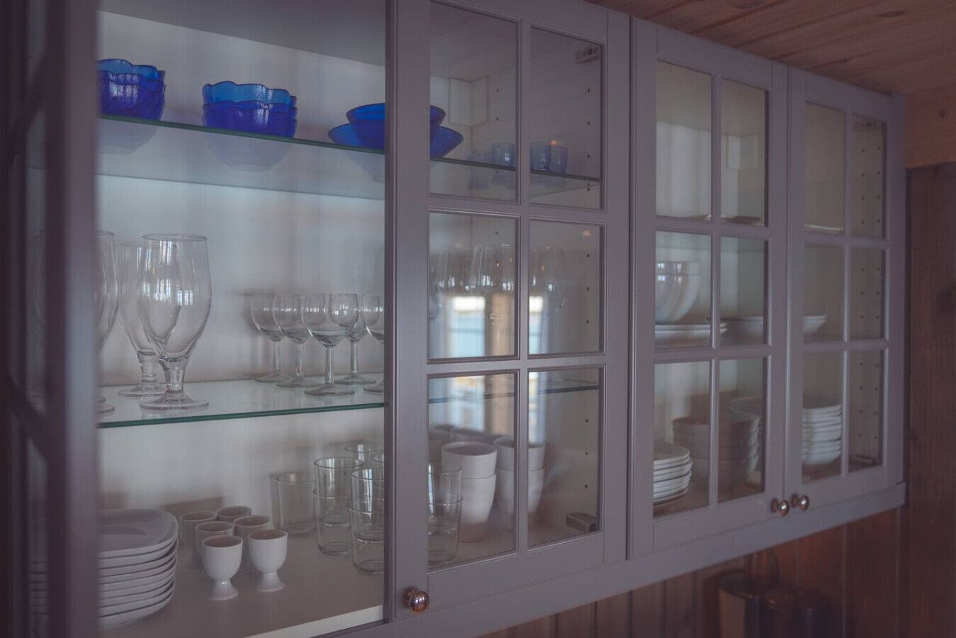 Eine gläserne Vitrine mit Regalen, gefüllt mit verschiedenen Gläsern und Geschirr.