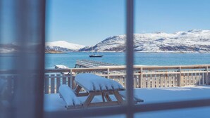 Une terrasse enneigée offrant une vue sur un lac paisible et des montagnes.