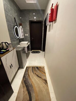 A modern bathroom with a dark door, a white sink, and a mirror with a lighted frame. - Al Salam Spacious Bedroom j7 (Jeddah)