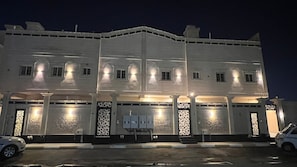 A multi-story building with illuminated windows and decorative gates, likely a hotel or office building. - Al Salam Spacious Bedroom j7 (Jeddah)