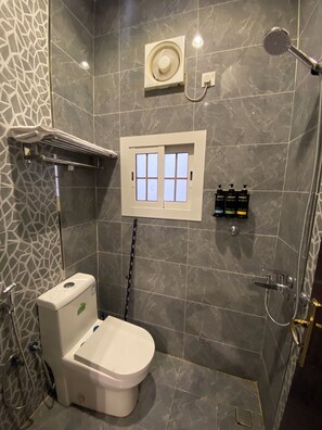 A modern bathroom with a toilet, shower, and a small window. - Al Salam Spacious Bedroom j7 (Jeddah)