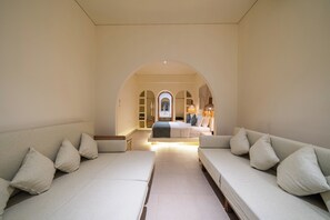 Ein Hotelzimmer mit zwei sich gegenüberliegenden Sofas, einem Himmelbett und einem Blick durch einen Bogen zur Badezimmereinrichtung.