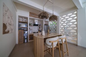 A modern kitchen with a central island, bar stools, and a decorative ceiling light fixture. - Velin Villa (Canggu)