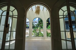 An open archway leading to a balcony with a view of a residential area and greenery. - Velin Villa (Canggu)