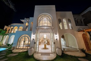 A multi-story building with arched windows and a central entrance with a chandelier. - Velin Villa (Canggu)
