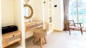 Ett rum med välvda tak, en träbänk, en flätad pall och ett stort fönster med gardiner.