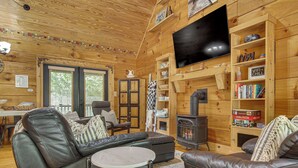 A cozy cabin interior with a fireplace, leather seating, a television, and wooden walls. - Hike, Bike, Tubing, Whitewater Rafting! Saluda Gem (Saluda)