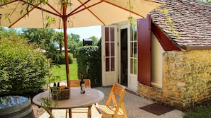 An outdoor patio with a round table, chairs, a wicker basket, and a bottle. - BERGER (Sainte-Foy-de-Longas)