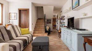 Una sala de estar con sofá, reposapiés, televisor y armarios.