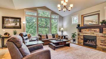 A living room with a fireplace, large windows, and a chandelier.