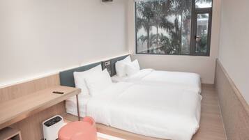 A modern hotel room with a large window, a bed, a desk, and a trash bin.