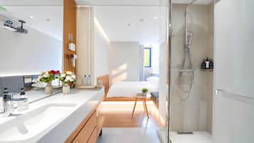 A modern hotel bathroom with a shower, a sink, and a toilet.