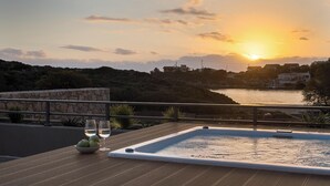 Een terras op het dak met een jacuzzi, twee glazen witte wijn en een schaal appels.