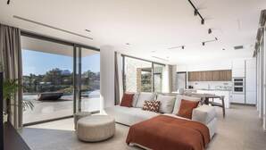 Een moderne woonkamer met een bank, voetenbankje en uitzicht op de omgeving.