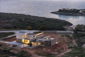 A modern house with a flat roof, solar panels, and a view of the sea. - Aeora Villa, Shoreline Getaway (Chania)