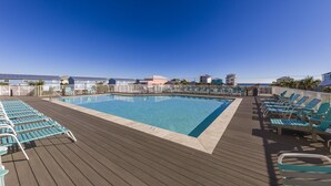 Un área de piscina con sillas de descanso y una terraza de madera.