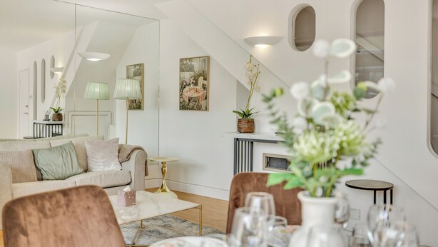 A modern living room with a sofa, dining table, chairs, and a fireplace. - LuxeLet St Giles Duplex Penthouse  (London)