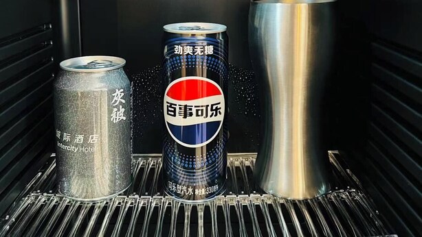 A refrigerator with a can of beverage, a glass, and a bottle. - IntercityHotel Shanghai Pujiang Center (Shanghai)