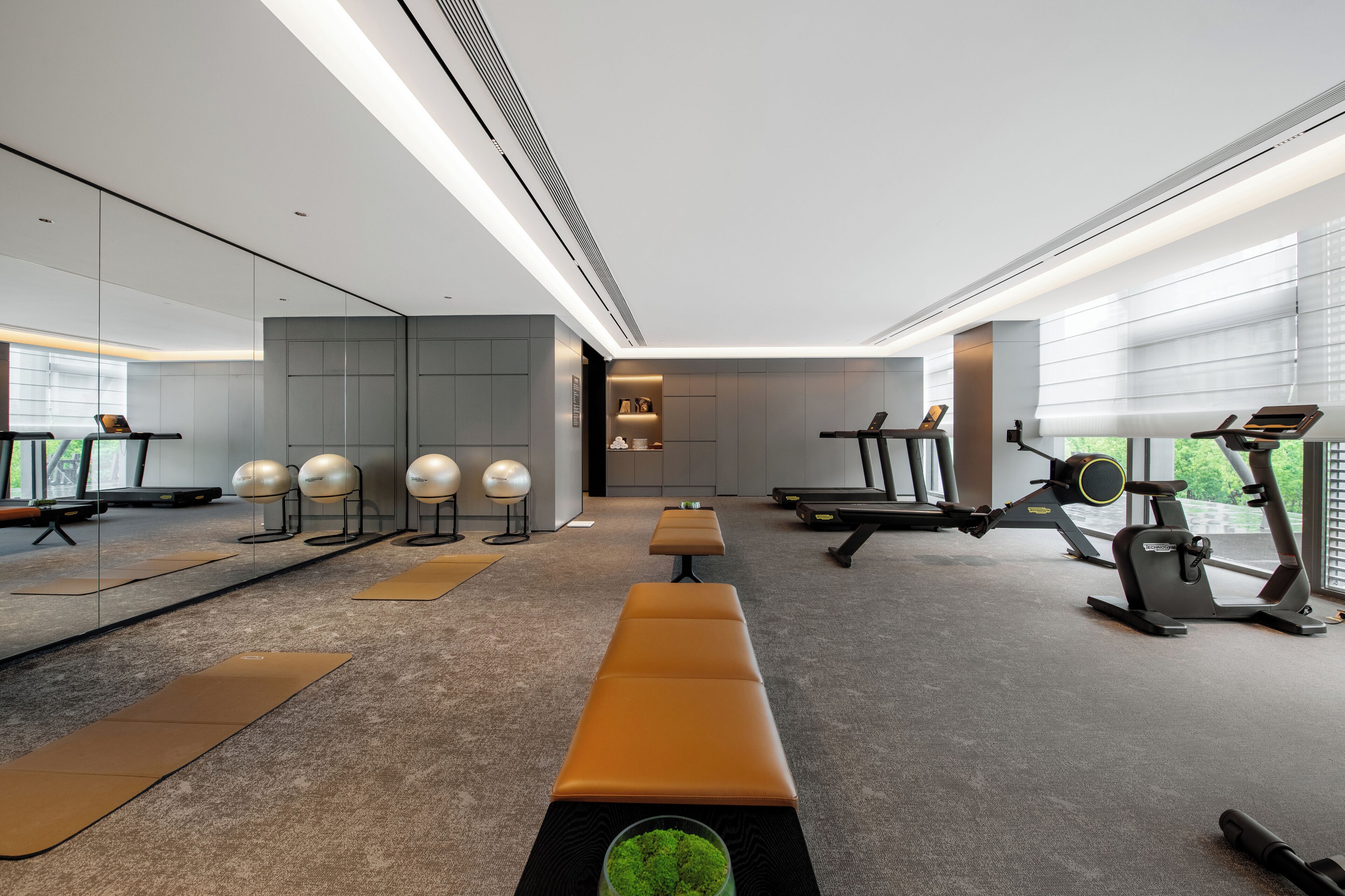 A modern gym with exercise equipment, a bench, and a mirror.