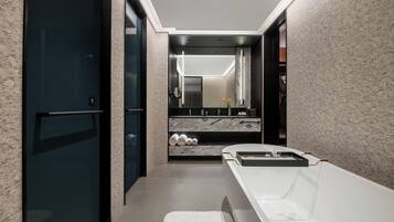 A modern bathroom with a large mirror, a bathtub, and a vanity with a marble countertop.