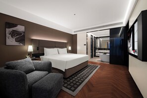 Une chambre d’hôtel moderne équipée d’un grand lit, d’un canapé, d’un bureau, d’une salle de bain et d’une télévision.