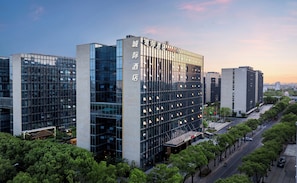 Een modern hotel met een glazen gevel, meerdere verdiepingen en een opvallende ingang.