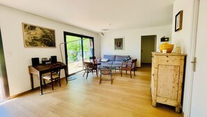 Un'ampia zona giorno con tavolo da pranzo, sedie, divano, un mobile e un'ampia finestra.