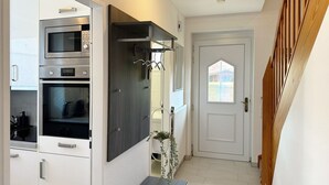A kitchen with modern appliances, a wooden staircase, and a white door with a window.