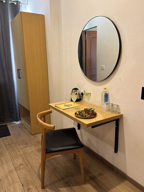 A small dining area with a wooden table, a chair, a mirror, and a plate of food.