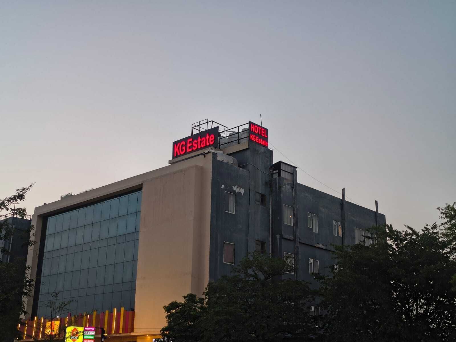 A hotel building with a modern glass facade and a prominent red sign indicating it is a KG Estate hotel.