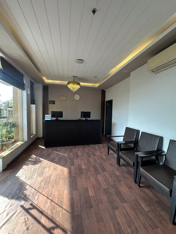 A reception area with a reception desk, two computer monitors, a chandelier, and a seating area with chairs. - HOTEL KG ESTATE (Jaipur)