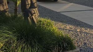 Ein Parkplatz mit einem schwarzen Auto, Kiesweg und Grünflächen.