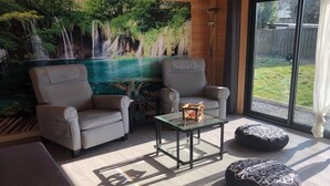 Une pièce comprenant deux chaises, une table en verre et deux poufs à motifs.