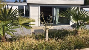 Un bâtiment moderne doté d’un toit plat, de grandes fenêtres et d’un petit arbre au premier plan.