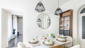 Een eetruimte met een ronde tafel gedekt voor vier personen, omringd door witte stoelen, met een houten kast en een spiegel aan de muur.