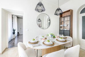 A dining area with a round table set for four, surrounded by white chairs, with a wooden cabinet and a mirror on the wall. - The beating heart of Lucca, at Casa Nara (Lucca)