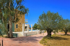 A building with a stone facade, a pool, and outdoor seating. - Afrodite Luxury Villa, Estrellas Luxury Villas (Kefalonia)