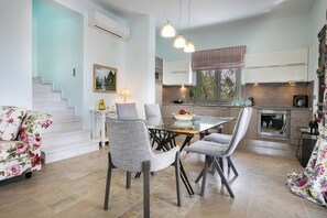 A modern kitchen with a dining table, chairs, and a staircase leading to an upper level. - Afrodite Luxury Villa, Estrellas Luxury Villas (Kefalonia)