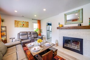 Una sala de estar con chimenea, una mesa de comedor preparada para cuatro personas y un sofá.