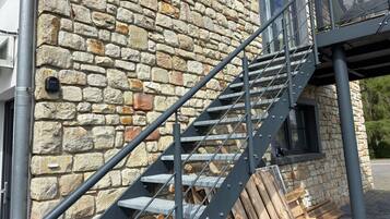 Un bâtiment en pierre avec un escalier métallique menant à une fenêtre.